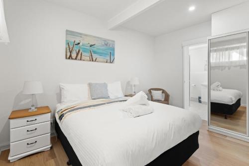 Habitación blanca con cama y espejo en Rye Beach Chalet - Downstairs Only, en Rye