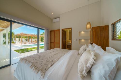 ein Schlafzimmer mit einem großen weißen Bett und einer Glasschiebetür in der Unterkunft Villa Air - Brand New Stylish 2BR Villa in Pererenan! in Munggu