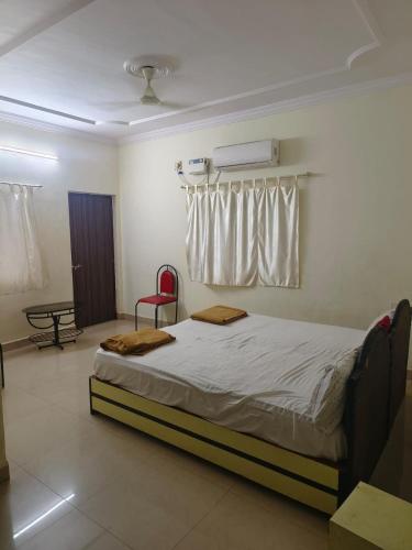 1 dormitorio con 1 cama y 1 silla roja en Flagship La Grande Residencya en Old Goa