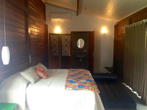 a bedroom with a white bed with a colorful blanket at Casa da Ilha do Mel - Pousada de Charme in Ilha do Mel