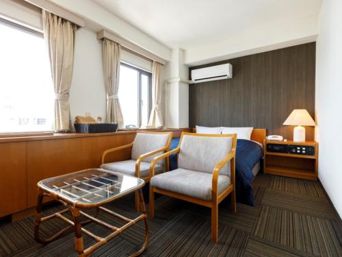 a hotel room with a bed and a chair and a table at Miyazaki Lions Hotel in Miyazaki