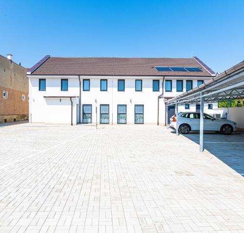 a large white building with a car parked in a parking lot at Elixír Panzió in Nyírbátor