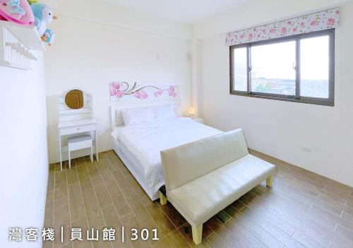 a white bedroom with a white bed and a chair at Yuanshan Dahu Homestay in Yuanshan