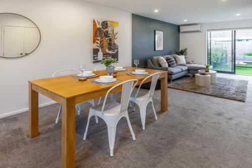 Un comedor con una mesa de madera y sillas blancas. en Central City Hideout, Location, Location! w/park, en Christchurch