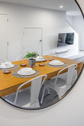 a dining room with a table with white chairs and a mirror at Central City Hideout, Location, Location! w/park in Christchurch