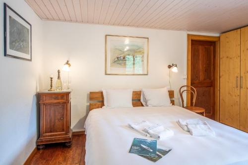a bedroom with a white bed and a wooden cabinet at Spitzenhaus Val Onsernone - Happy Rentals in Vergeletto