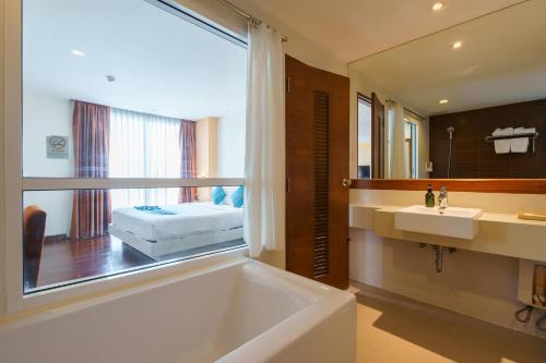 Lantana Resort Hotel Bangkok في بانكوك: حمام مع حوض ومغسلة ومرآة