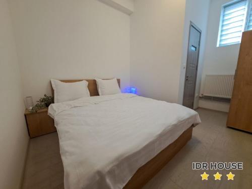 um quarto com uma cama grande com lençóis brancos e almofadas em IDR HOUSE em Buzău