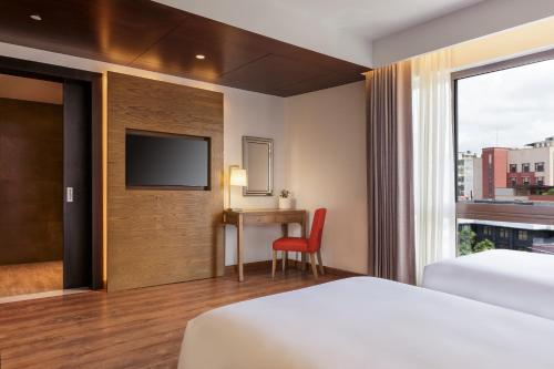 a hotel room with a bed and a desk and a tv at Dusit Princess Kathmandu in Kathmandu