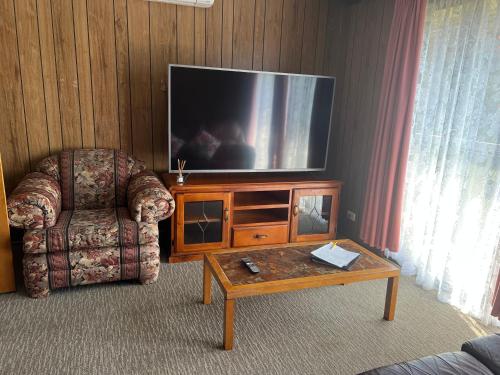 a living room with a tv and a chair and a coffee table at Woodmans Hill Motel in Ballarat