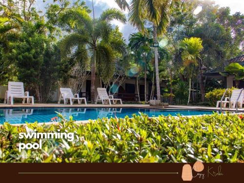 a swimming pool with lawn chairs and palm trees at Cozy Saithai Krabi in Krabi