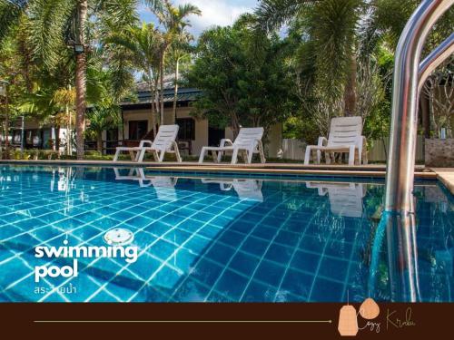 a swimming pool with white chairs and palm trees at Cozy Saithai Krabi in Krabi