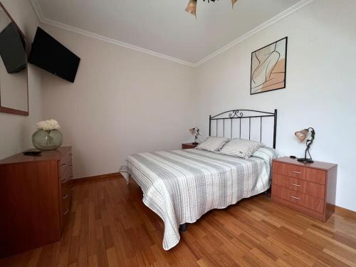 a bedroom with a bed and a television in it at Apartamento Cantabrico vistas a la Ría deRibadeo in Ribadeo
