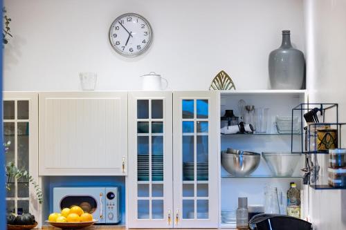 a kitchen with white cabinets and a clock on the wall at הבית בראש פינה - The House in Rosh Pinna