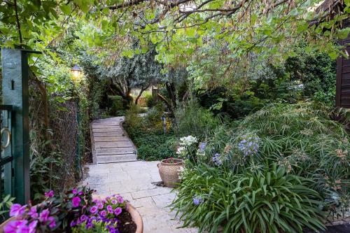 a garden with a path with flowers and plants at הבית בראש פינה - The House in Rosh Pinna