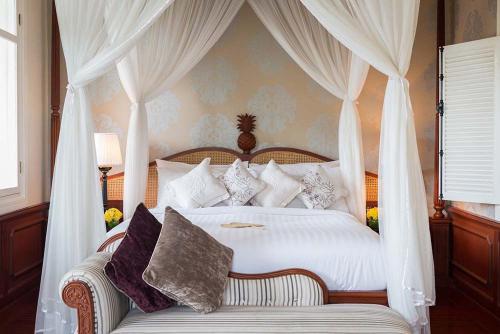 a bedroom with a white canopy bed with pillows at The Luang Say Residence in Luang Prabang