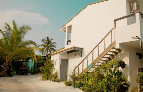 a white building with a staircase and palm trees at My House in Vashafaru