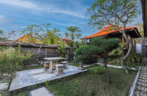 a garden with a picnic table and trees and a building at Swan Beach Inn in Nusa Penida
