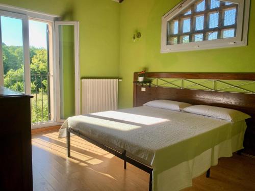 a bedroom with a bed with green walls and a window at Le Casette di Olga -Space for Nature and Sport Lovers- in Baone