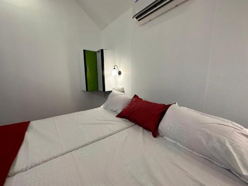 - un lit blanc avec des oreillers rouges et blancs dans l'établissement Coastal Cabana Marari, à Mararikulam