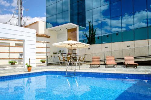 uma piscina com um guarda-sol e cadeiras e uma mesa com um guarda-sol em Hospedería Mirador de Llerena em Llerena