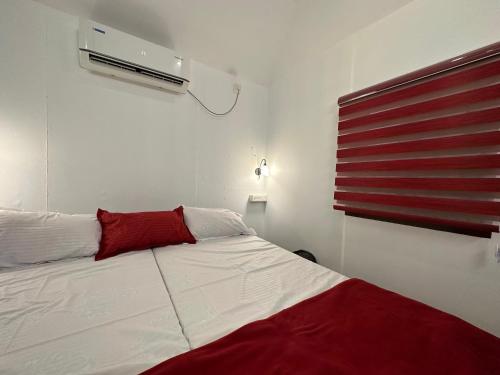 Schlafzimmer mit einem weißen Bett und einem roten Kissen in der Unterkunft Coastal Cabana Marari in Mararikulam