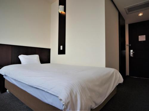 a bedroom with a large bed with white sheets at Green Rich Hotel Tosu Ekimae in Tosu