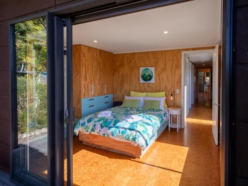 1 dormitorio con 1 cama y puerta corredera de cristal en Bach 7 by The Sea - Marahau Holiday Home, en Marahau