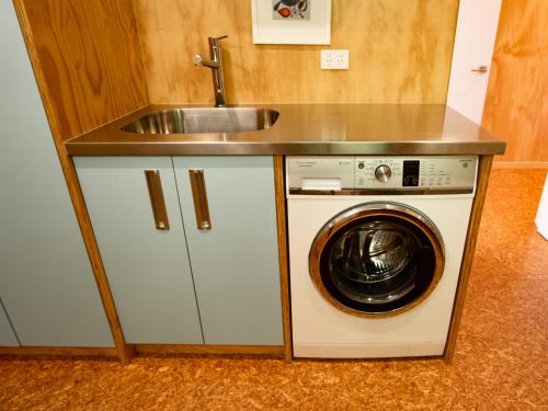 uma cozinha com um lavatório e uma máquina de lavar roupa em Bach 7 by The Sea - Marahau Holiday Home em Marahau