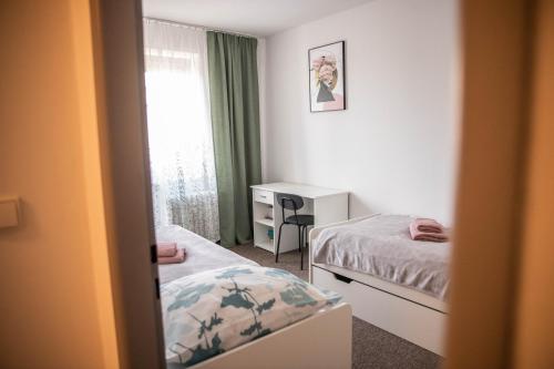 a bedroom with two beds and a desk and a window at Prostorný byt v centru u řeky, 2 ložnice, balkón in Hradec Králové