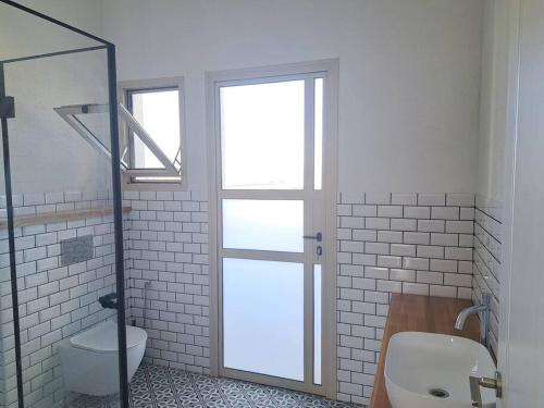 a bathroom with a toilet and a glass shower door at וילה אקרופוליס Villa Acropolis in ‘En Dor