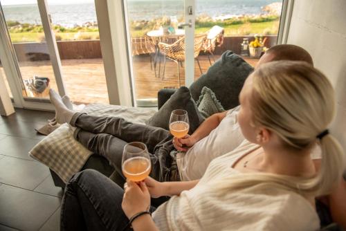 カルドラにあるMerevaatega majutus Kärdla sadamasのワインを二杯持つソファに座る女性