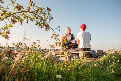 a man and woman sitting on a bench in a field at Merevaatega majutus Kärdla sadamas in Kärdla