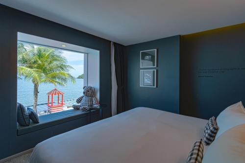 1 dormitorio con ventana grande con vistas al océano en foto Hotel Phuket en Phuket
