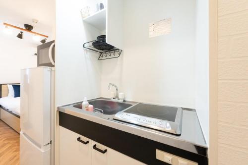 a kitchen with a sink and a refrigerator at Verde Ikebukuro in Tokyo