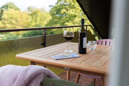 uma garrafa de vinho e um copo numa mesa de madeira em fuldaliebe - Stadtnahe moderne Ferienwohnung in Fulda em Fulda