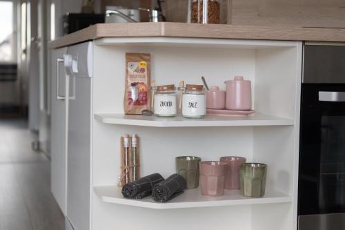 a shelf with pink items on it in a kitchen at fuldaliebe - Klimatisierte moderne Ferienwohnung in Fulda in Fulda