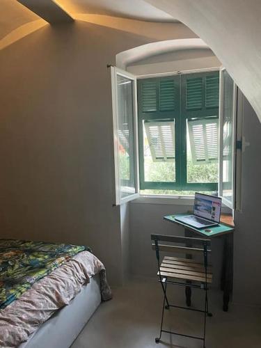 ein Schlafzimmer mit einem Bett und einem Laptop auf einem Tisch neben einem Fenster in der Unterkunft My little beach cabin in Ventimiglia
