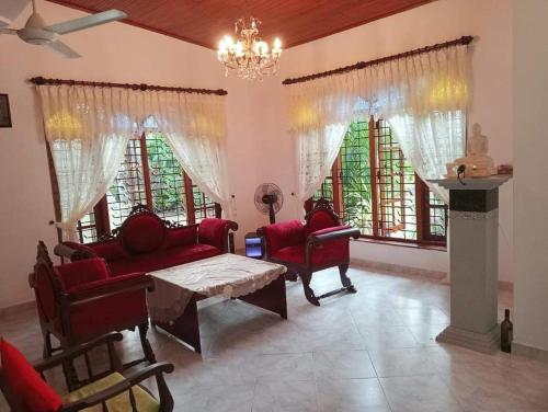 Mal villa في يوناواتونا: غرفة معيشة مع كراسي حمراء وطاولة ونوافذ