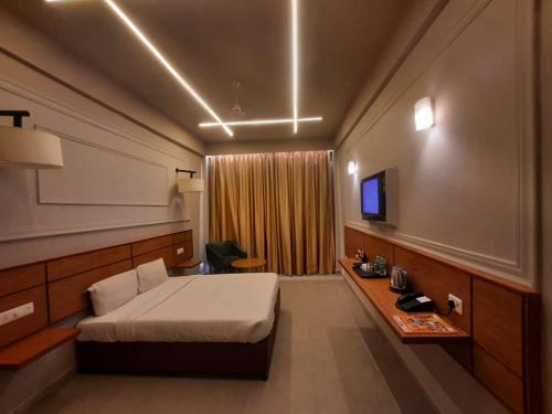Habitación de hotel con cama y TV en Max Hotels Prayagraj, en Allahābād