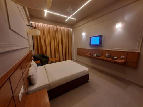 Habitación de hotel con cama y TV en Max Hotels Prayagraj, en Allahābād