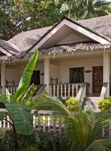 a small house with a thatched roof and a garden at Easy Diving and Beach Resort in Sipalay