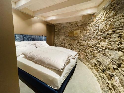 Cama en habitación con pared de piedra en Der Turm Leiben Apartments, en Leiben