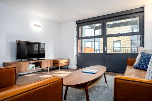 a living room with a couch and a tv and a table at Modern & Spacious 2 Bedroom in Central London in London