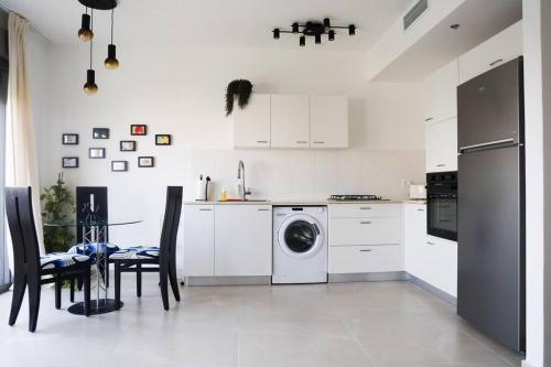 a white kitchen with a washing machine and a table at Space age Jaffa Apartment in Tel Aviv