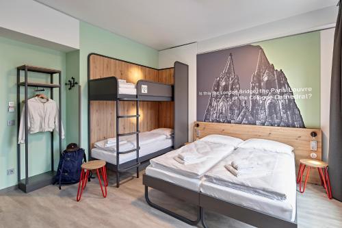 a bedroom with two bunk beds and two stools at MEININGER Hotel Köln West in Cologne