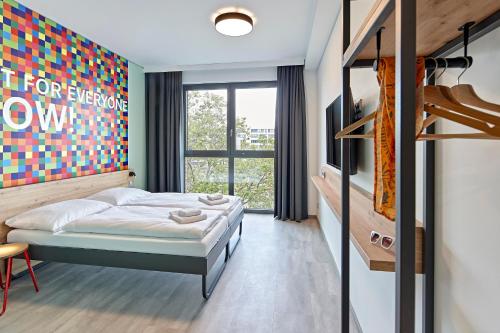 a bedroom with a bed and a large window at MEININGER Hotel Köln West in Cologne