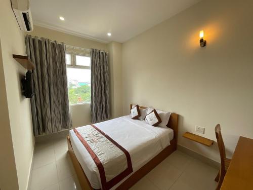 a hotel room with a bed and a window at Quê Tôi 2 Hotel in Soc Trang