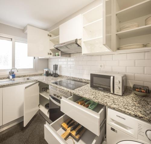 eine weiße Küche mit weißen Schränken und einer Mikrowelle in der Unterkunft Macflats Ciudad de las Ciencias in Valencia