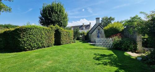 a house with a yard with green grass at Gîte 4 personnes avec piscine et bain nordique proche des plages du débarquement in Le Manoir